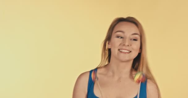黄色の背景に 2 色のキャンディーを持つ女性の浮気 - 映像、動画