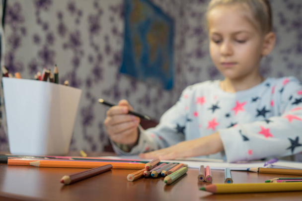 Attentive child writes with crayons on the album. Homework. Childrens creativity. - Valokuva, kuva