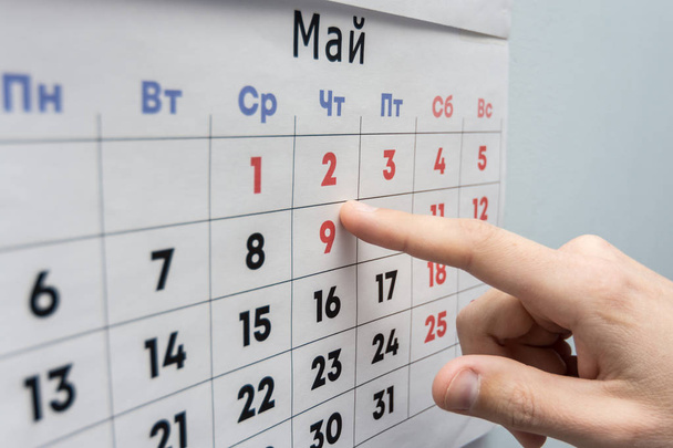 La mano señala las vacaciones del 2 de mayo en una hoja de calendario de pared - Foto, Imagen