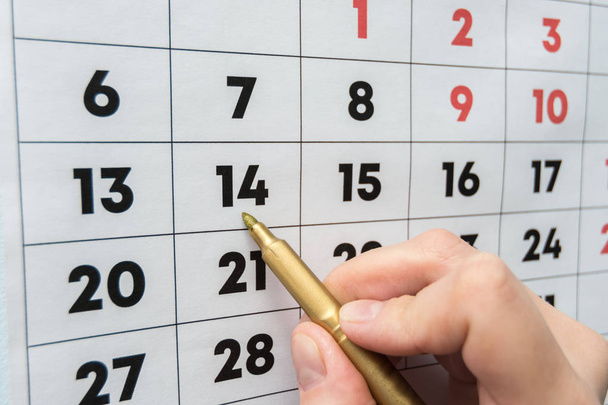 Hand marker indicates the date on the wall calendar - Photo, Image