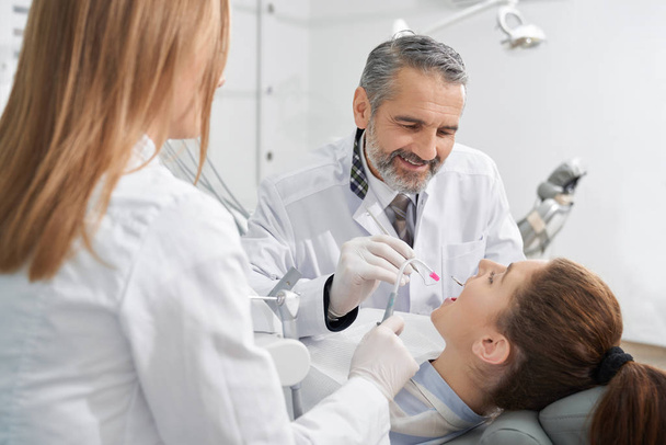 View from side of positive male dentist treating teeth - Фото, зображення