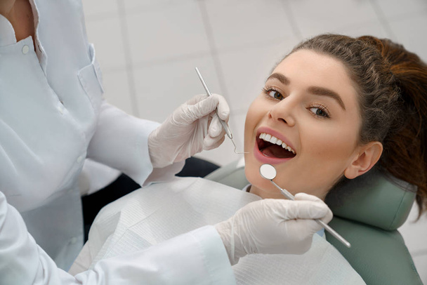 Mujer con la boca abierta mirando la cámara en el consultorio dental
 - Foto, Imagen
