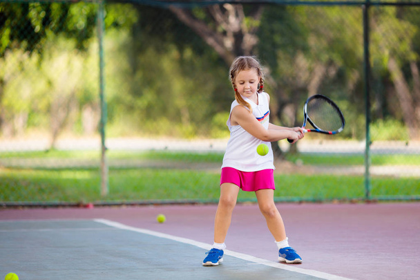 Child playing tennis on indoor court. Little girl with tennis racket and ball in sport club. Active exercise for kids. Summer activities for children. Training for young kid. Child learning to play. - Φωτογραφία, εικόνα