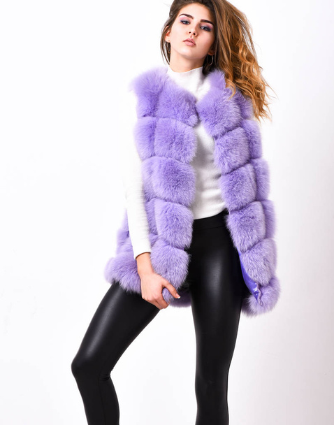 Winter fashionable wardrobe for female. Boutique selling fur. Violet fur vest fashion clothing. Woman makeup face wear fur vest white background. Luxury fur clothes for female. Fashion trend concept - 写真・画像