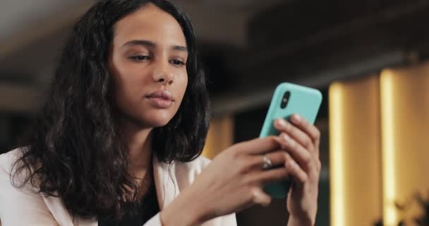 Νεαρή γυναίκα επιχειρηματική χρήση κινητού τηλεφώνου στο άνετο κατάστημα καφέ. Αυτή την περιήγηση μηνύματα σε απευθείας σύνδεση και απαντώντας σε κείμενα - Πλάνα, βίντεο
