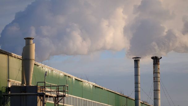 Planta de procesamiento de madera con humo sobre fondo azul cielo. Industria maderera
 - Foto, Imagen