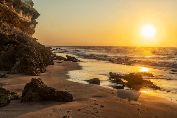 Beautiful sunset on the Namibe wild beach, Africa. Angola. With cliff and rocks. - Photo, Image