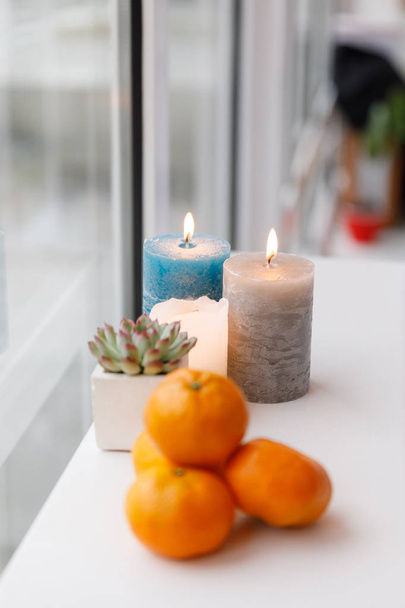 Latte op een houten dienblad, kaarsen en mandarijnen. Gezellige koffiepauze thuis - Foto, afbeelding