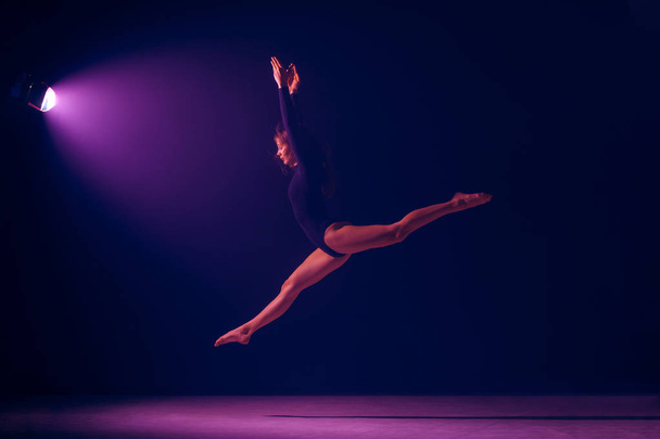 Young female ballet dancer on neon lights studio background. - Fotografie, Obrázek