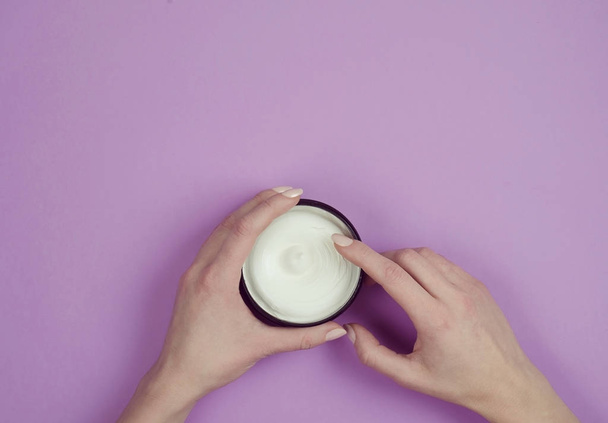 Moisturizing body cream in a jar on a lilac background - 写真・画像