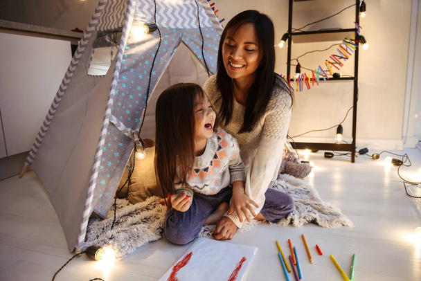 Image of an amazing young asian woman with her little daughter having fun on floor. Christmas concept. - Valokuva, kuva