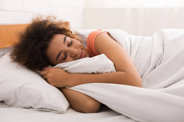 Αφρικανικός-αμερικανική γυναίκα στον ύπνο και αγκαλιάζει άσπρη κουβέρτα - Φωτογραφία, εικόνα