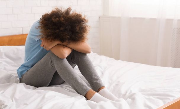 African-american woman suffering from depression sitting on bed - Photo, Image