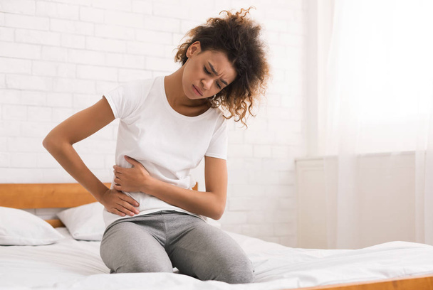 afro-américaine fille souffrant de douleurs abdominales sur le lit
 - Photo, image