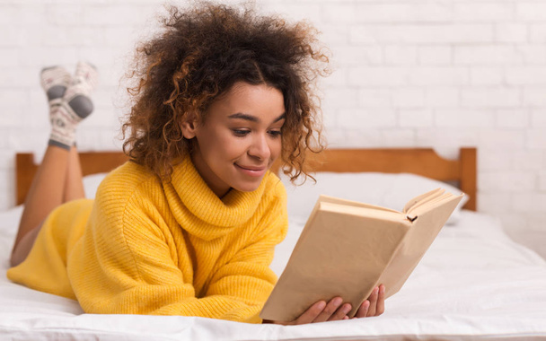 Relajada chica leyendo libro en la cama en casa
 - Foto, Imagen
