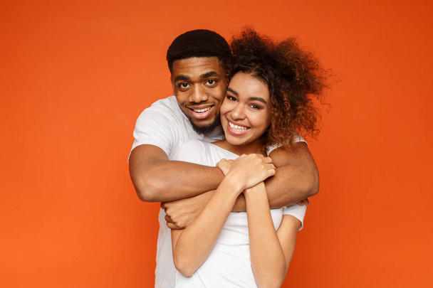 Joven pareja afroamericana encantadora posando sobre fondo naranja
 - Foto, Imagen