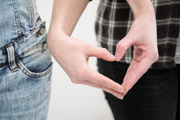 Two girls in jeans hold hands close up. White background. Homosexual lesbian couple. - 写真・画像