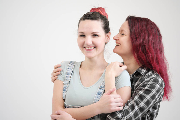 Two girls hug on a white background. Homosexual lesbian couple. Casual clothes. - Photo, Image