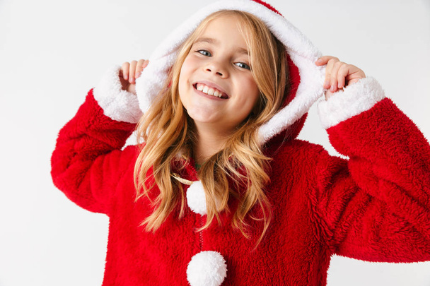 Cute cheerful little girl wearing Christmas costume isolated over red background - Fotó, kép