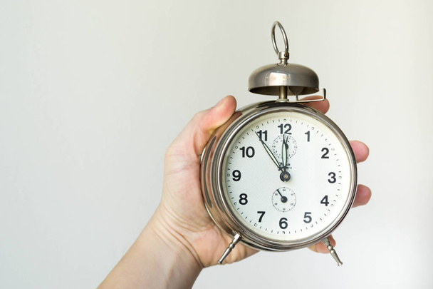 kezében egy ébresztőóra mutatja időt - öt perc alatt tizenkét - óra szembenéz - Fotó, kép