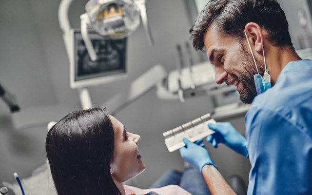 Attractive young woman in stomatology clinic with male dentist. Healthy teeth concept. - 写真・画像