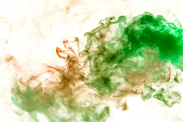 Λεπτή ρέματα γκρι καπνού φιμέ στο πράσινο σε ένα λευκό φόντο σαν ακουαρέλα διάλυση σε νερό. - Φωτογραφία, εικόνα
