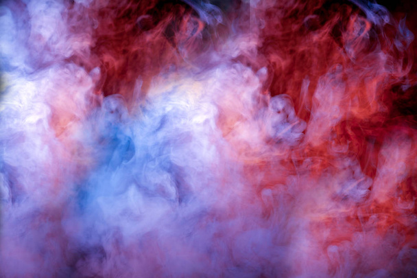 De combinatie van de mooie kleur van blauw, roze, paarse en rode tinten van de stof is rook, op een zwarte achtergrond, dat lijkt op de Melkweg. - Foto, afbeelding