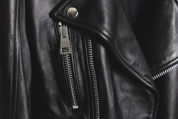 schwarze Lederjacken mit metallischem Reißverschluss und Knöpfen. klassische Kleidung für Biker. Detaillierte Nahaufnahme. - Foto, Bild
