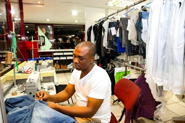 Johannesburg, South Africa - April 27 2011: African Man repairing clothes at a Dry Cleaner - Fotó, kép