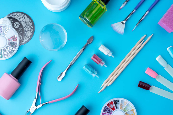 Un conjunto de herramientas cosméticas para manicura profesional, cuidado de uñas y para crear hermosos diseños sobre un fondo azul. Vista superior
 - Foto, imagen