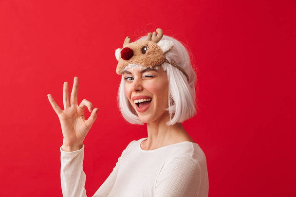 Image of a young happy woman dressed in carnival christmas costume posing isolated over red wall background. - Фото, зображення