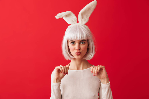 Image of a young happy woman dressed in carnival christmas bunny costume posing isolated over red wall background. - Fotografie, Obrázek
