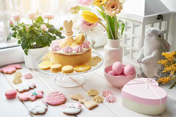 Bolo de Páscoa com pão de gengibre na mesa, a mesa é decorada com flores, coelhos e ovos
 - Foto, Imagem