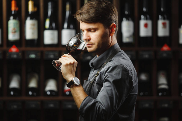 Bokal of red wine on background, male sommelier appreciating drink - Foto, imagen