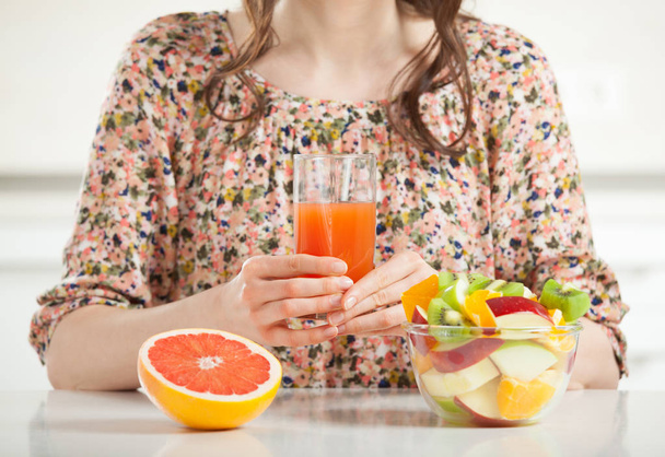 Unrecognizable woman having healthy breakfast: fresh fruit salad, a glass of juice and appetizing grapefruit - 写真・画像