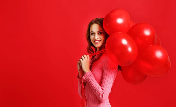 young beautiful emotional girl in pink dress with red ballons on red backgroun - Photo, Image