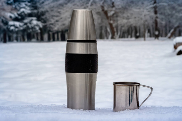 Thermoskanne und Tasse im Winter im Freien. Wandern - Foto, Bild