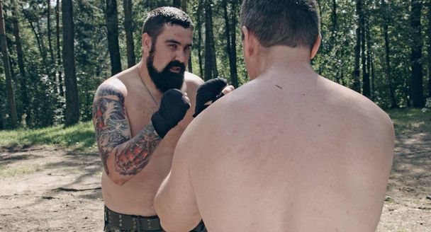 two caucasian men practicing box blows in forest camp - Photo, image