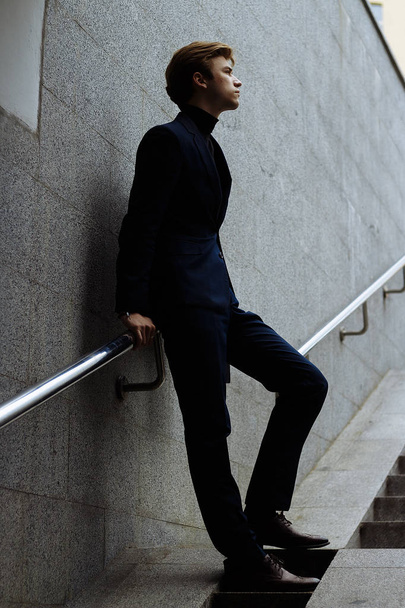 thin, attractive man is leaning on the railing, on the stairs. looking up. underground. win.take a step. - 写真・画像