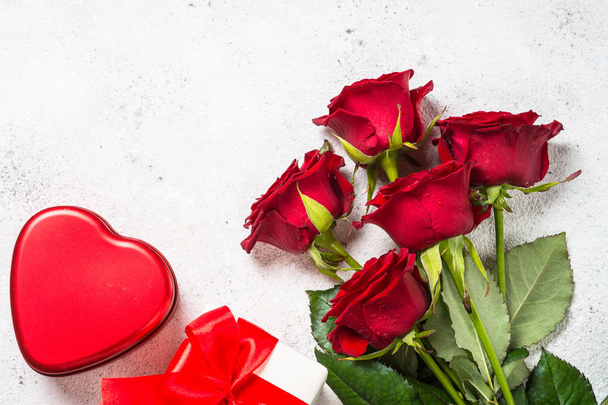 Φόντο ημέρα του Αγίου Βαλεντίνου. Κόκκινα τριαντάφυλλα, καρδιές και παρόν σε λευκό. - Φωτογραφία, εικόνα