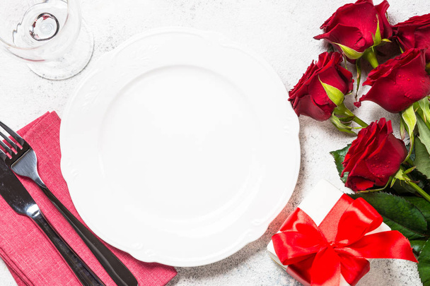 Table de Saint Valentin avec assiette, roses et cadeau
.  - Photo, image