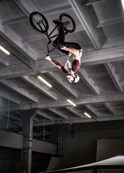 Young BMX making crazy tricks on his bicycle in skatepark indoors. - Foto, Bild