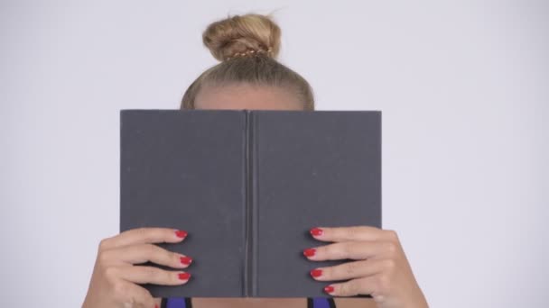 Young beautiful blonde woman covering face with book - Felvétel, videó