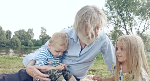 kaukaski dziadek z wnukiem i wnuczką spędzają czas na łonie natury - Materiał filmowy, wideo