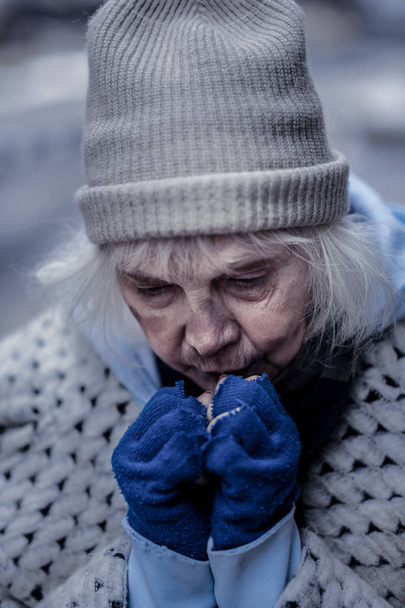 Depressed homeless woman trying to warm her hands - Fotó, kép
