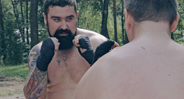 two caucasian men practicing box blows in forest camp - Foto, immagini