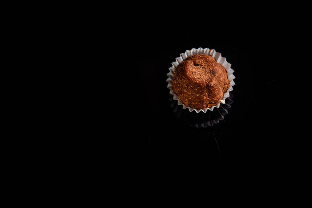 top view on healthy useful organic handmade chocolate candy decorated with brown cocoa powder on black mirror background - Foto, immagini