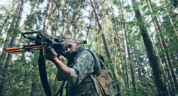 closeup view of man in camouflage with crossbow in forest - Fotó, kép