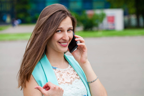 Beautiful young brunette woman calling by phone, summer street outdoors - Фото, зображення