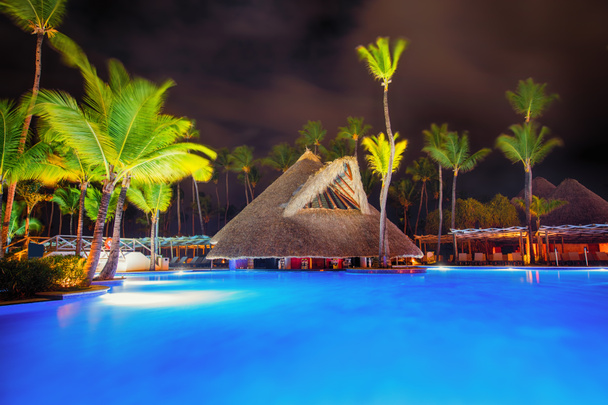 Tropical swimming pool and palm trees in luxury beach resort at night - Photo, Image